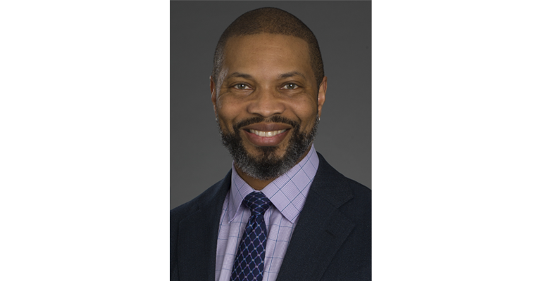 Turahn Dorsey smiles at the camera wearing a suit jacket and tie
