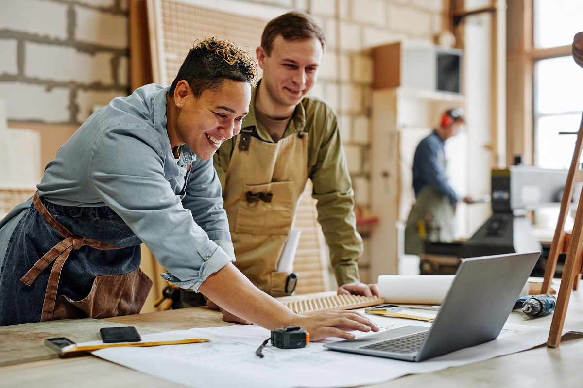 Colleagues stand over a work table and review business information on a laptop