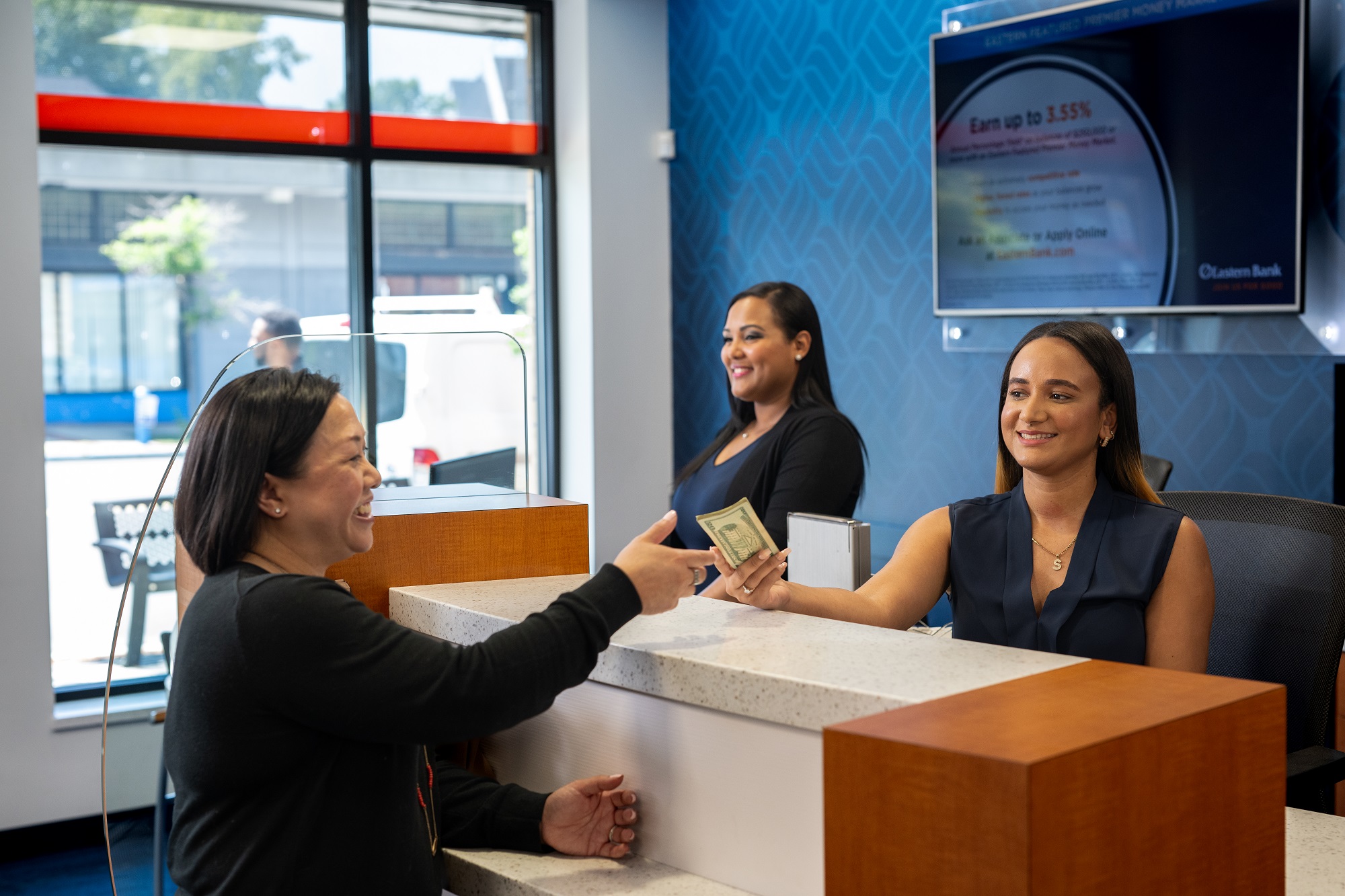 A customer receives money from an Eastern Bank teller after conducting a transition in the bank