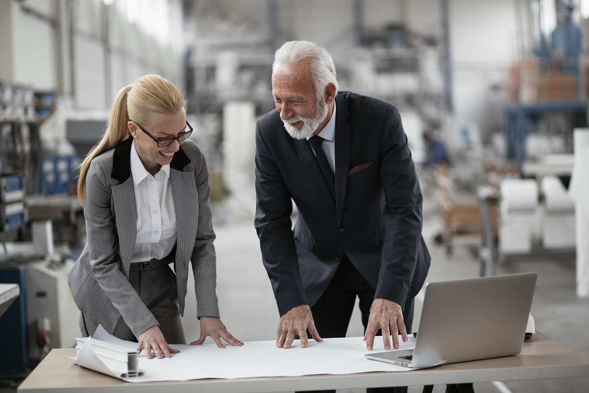 Two business owners review financials on a laptop while visiting the warehouse