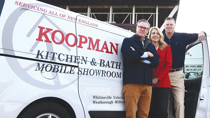 The three owners of Koopman Lumber stand in front of one their mobile showroom vans and smile at the camera