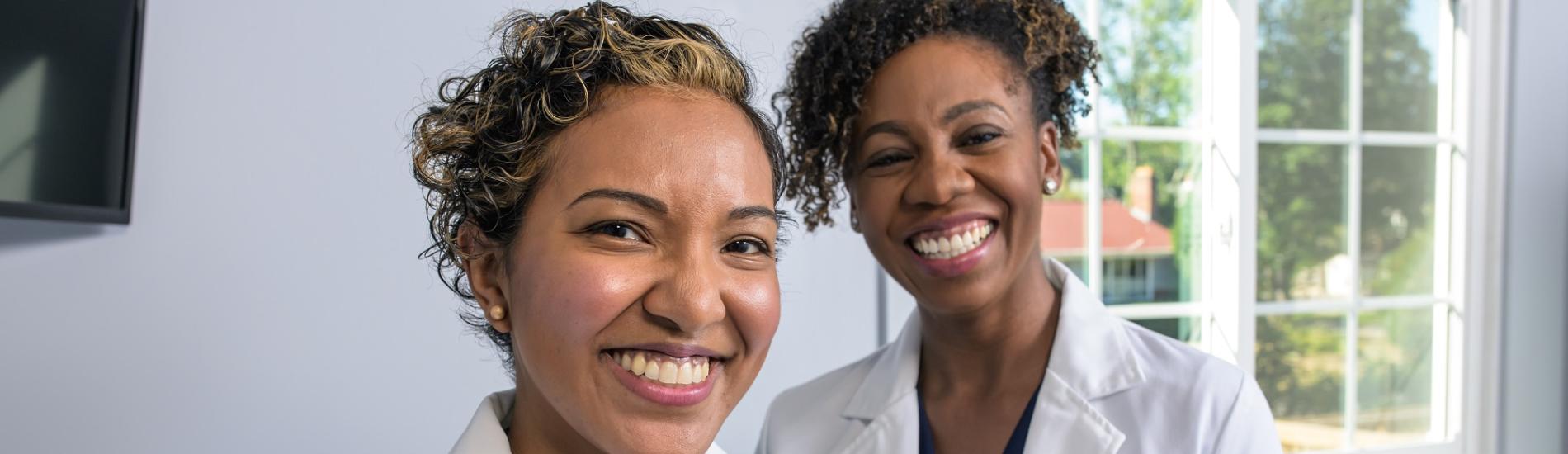 Two doctors smile for the camera at the dental practice that they own