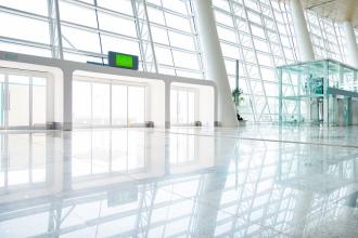 An entry of a large building made of glass with a marble floor