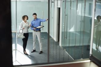 Colleagues stand outside of a glass office