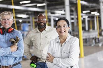 Colleagues stand together in a commercial facility and smile at the camera