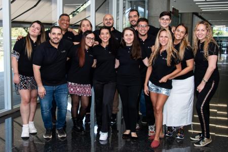 Roads Consulting Group team members stand together in branded black polo shirts and smile at the camera