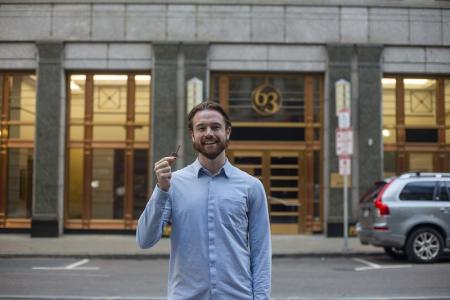 Connor Schoen stands in front of a building in Boston and holds up the building key