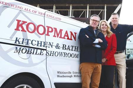 The three owners of Koopman Lumber stand in front of one their mobile showroom vans and smile at the camera