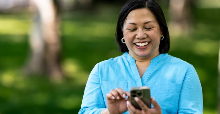 A woman views her bank account on her mobile phone